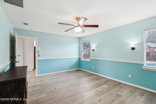 empty room with ceiling fan, wood finished floors, a textured ceiling, and baseboards