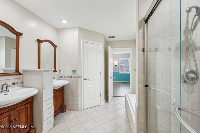 full bath with a shower stall, tile patterned flooring, a garden tub, two vanities, and tile walls