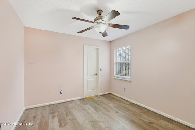 empty room featuring light wood-style flooring, a ceiling fan, and baseboards