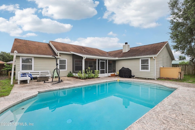 view of pool with a sunroom, fence, and a patio
