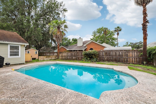 view of swimming pool featuring a storage unit, an outbuilding, and a fenced backyard