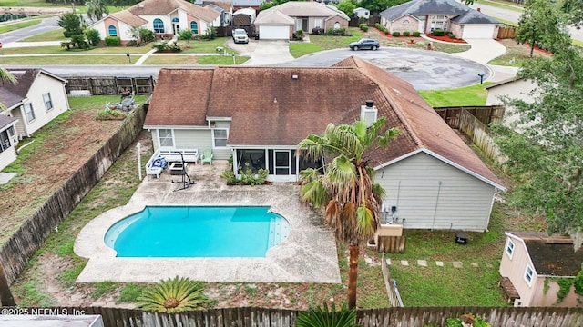view of pool featuring a fenced backyard, a residential view, a patio area, and a sunroom