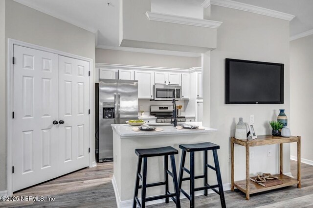 7800 Point Meadows Dr Unit 1511, Jacksonville, FL 32256 - kitchen featuring ornamental molding, stainless steel appliances, white cabinetry, light wood-style floors, and a kitchen breakfast bar