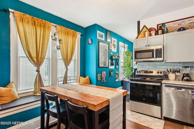 kitchen with light countertops, light wood-style flooring, decorative backsplash, and stainless steel appliances