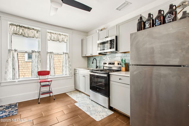 kitchen featuring tasteful backsplash, visible vents, a sink, light countertops, and appliances with stainless steel finishes