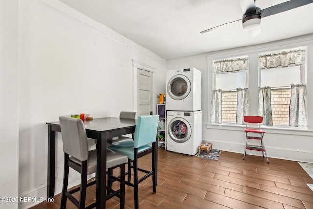laundry room featuring baseboards, stacked washer / drying machine, laundry area, ceiling fan, and wood finished floors