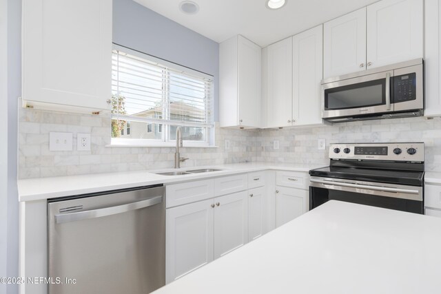 476 Monet Ave, Ponte Vedra, FL 32081 - kitchen with decorative backsplash, white cabinets, a sink, and appliances with stainless steel finishes