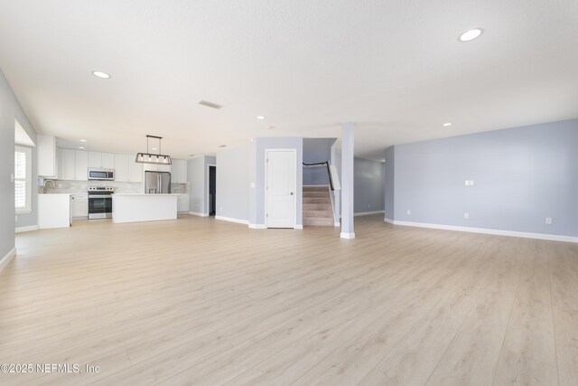 476 Monet Ave, Ponte Vedra, FL 32081 - unfurnished living room featuring baseboards, light wood-type flooring, stairway, and a sink