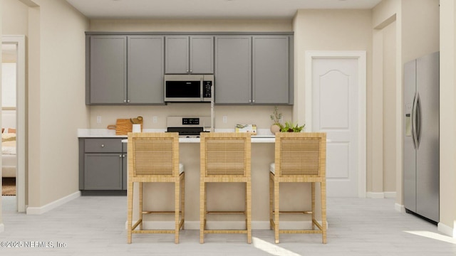 kitchen with light countertops, electric range oven, stainless steel refrigerator with ice dispenser, gray cabinetry, and a breakfast bar area