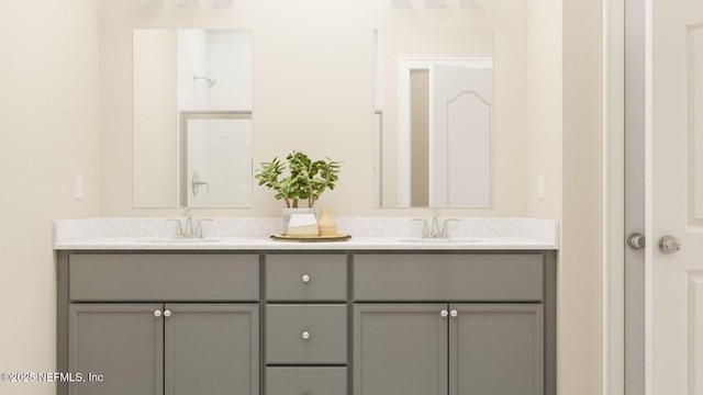 full bath with double vanity, a sink, and walk in shower
