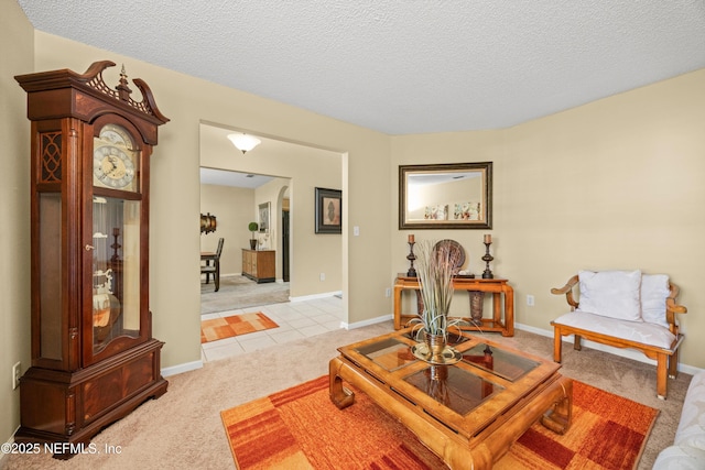 sitting room featuring light tile patterned floors, baseboards, a textured ceiling, and light carpet