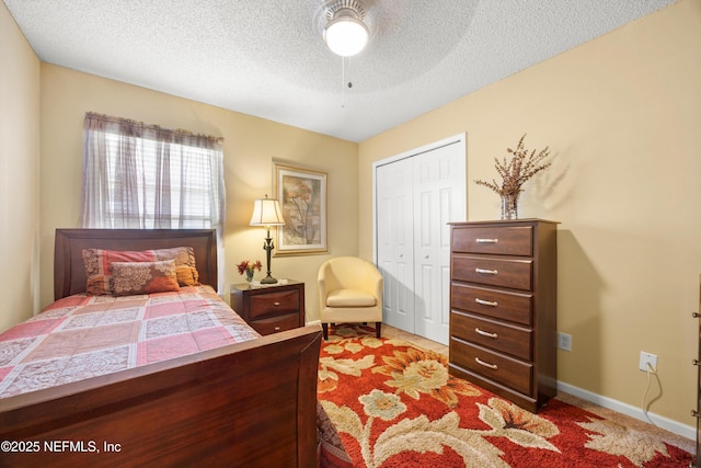 bedroom with a textured ceiling, ceiling fan, a closet, baseboards, and carpet floors