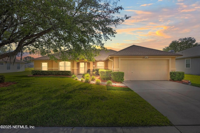 ranch-style home with a lawn, driveway, a garage, and stucco siding