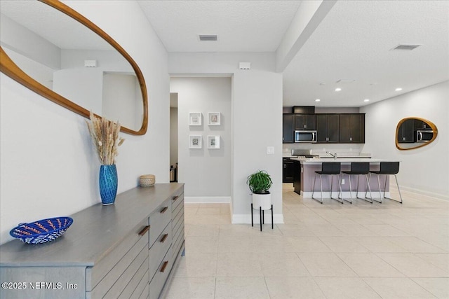 55 Cool Springs Ave, Ponte Vedra, FL 32081 - interior space featuring a kitchen bar, stainless steel microwave, baseboards, a textured ceiling, and visible vents