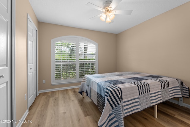 bedroom with ceiling fan, light wood finished floors, and baseboards