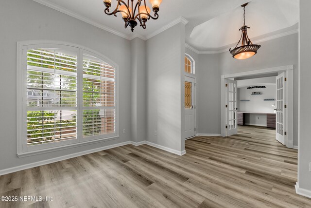 unfurnished dining area featuring a chandelier, light wood-type flooring, baseboards, and crown molding