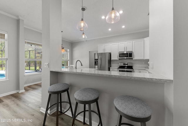 kitchen featuring backsplash, crown molding, white cabinets, light stone countertops, and appliances with stainless steel finishes