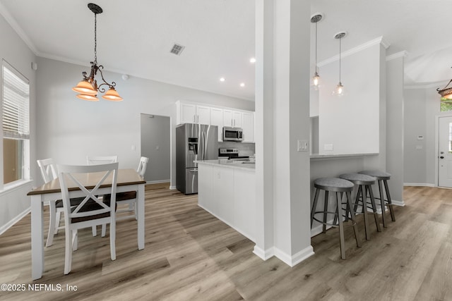 kitchen with visible vents, white cabinets, ornamental molding, appliances with stainless steel finishes, and light wood-style flooring