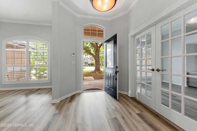 foyer featuring crown molding, french doors, baseboards, and light wood finished floors
