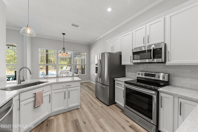 kitchen featuring visible vents, white cabinets, a sink, appliances with stainless steel finishes, and crown molding