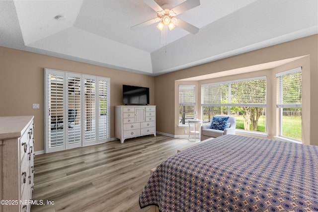bedroom featuring a tray ceiling, light wood-style flooring, and baseboards