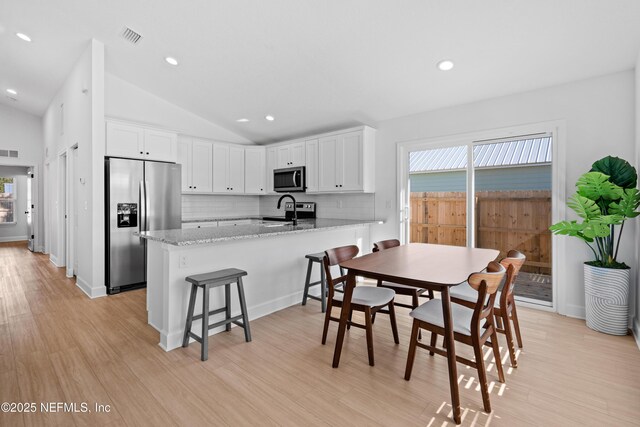 65 Josiah St, Saint Augustine, FL 32084 - kitchen with white cabinetry, a peninsula, stainless steel appliances, and vaulted ceiling