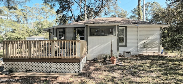 rear view of house featuring a deck, central AC unit, and roof with shingles