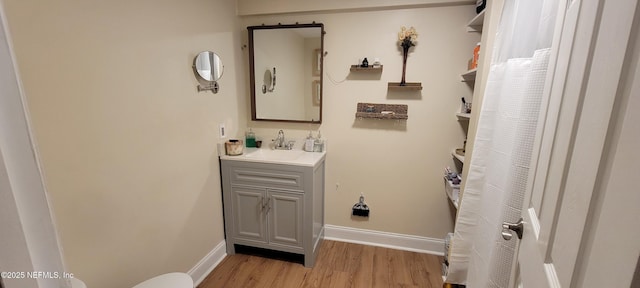 bathroom with baseboards, wood finished floors, and vanity