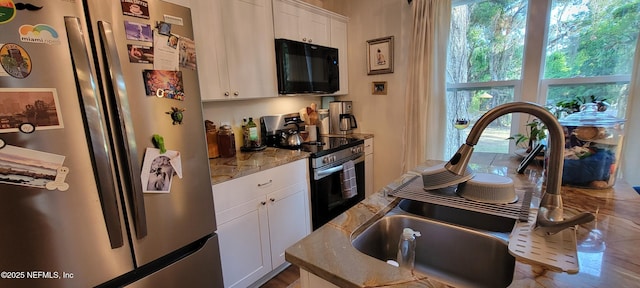 kitchen featuring white cabinetry, appliances with stainless steel finishes, stone counters, and a sink
