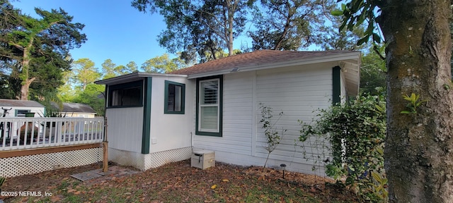 view of property exterior featuring roof with shingles and a deck