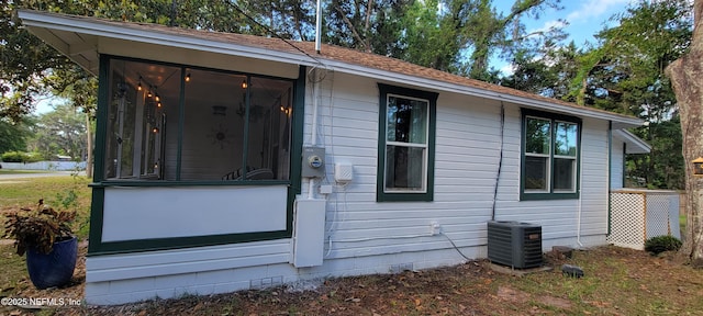 exterior space with central air condition unit and a sunroom
