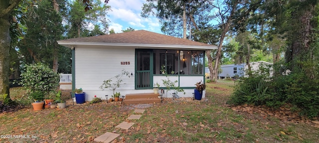 rear view of house with a shingled roof and a sunroom