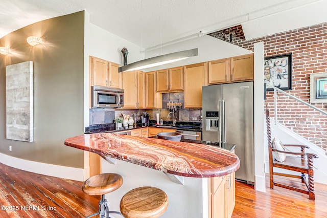 301 E Bay St Unit 405, Jacksonville, FL 32202 - kitchen with light brown cabinets, a kitchen bar, light wood-style floors, stainless steel appliances, and decorative backsplash