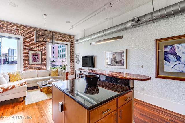 301 E Bay St Unit 405, Jacksonville, FL 32202 - kitchen with track lighting, brick wall, open floor plan, a textured wall, and light wood-style floors