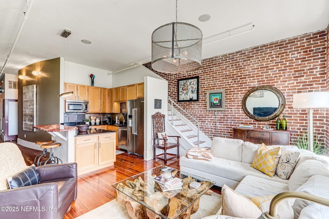 301 E Bay St Unit 405, Jacksonville, FL 32202 - living room featuring light wood-style floors, brick wall, visible vents, and stairway