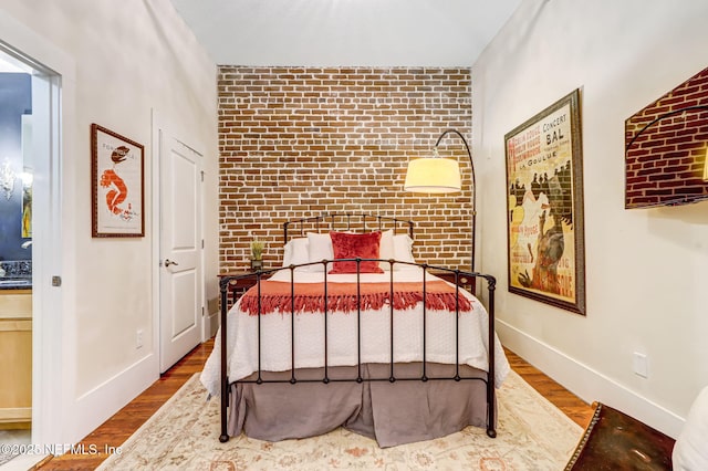 301 E Bay St Unit 405, Jacksonville, FL 32202 - bedroom with brick wall, wood finished floors, baseboards, and an accent wall