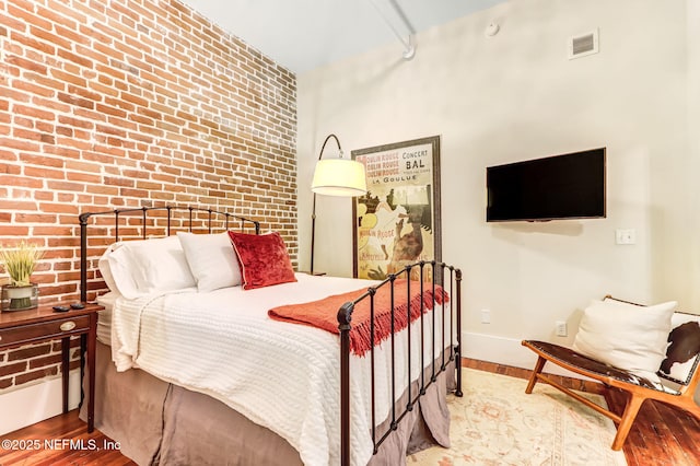 301 E Bay St Unit 405, Jacksonville, FL 32202 - bedroom with visible vents, brick wall, wood finished floors, and baseboards