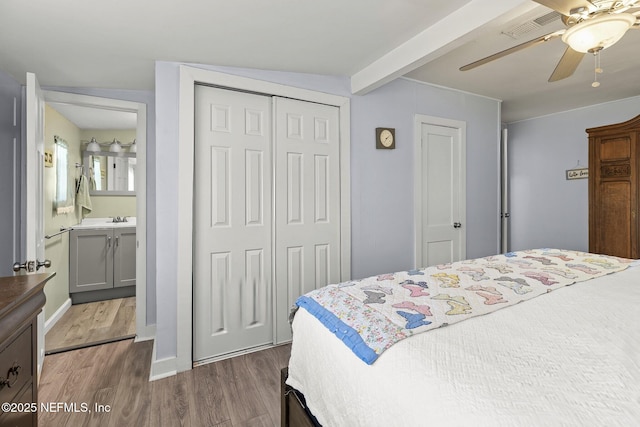 bedroom featuring dark wood-type flooring, a closet, a ceiling fan, visible vents, and beam ceiling