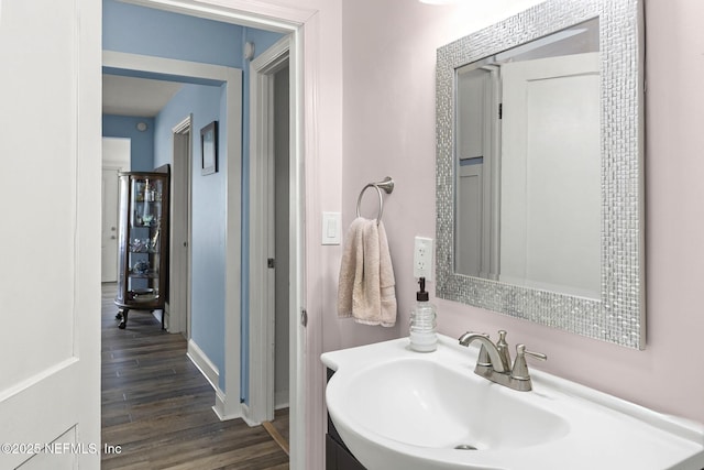 bathroom featuring wood finished floors, a sink, and baseboards