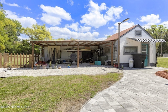 view of front of house with an outbuilding, a front yard, and fence