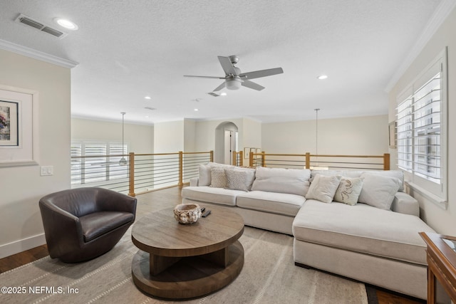 living room with a wealth of natural light, visible vents, wood finished floors, and ceiling fan