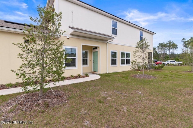 rear view of property with a lawn and stucco siding