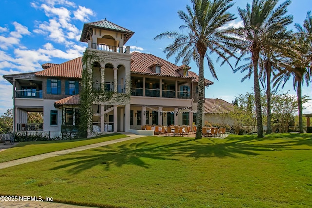 rear view of property featuring a balcony, a tiled roof, a yard, and a patio area