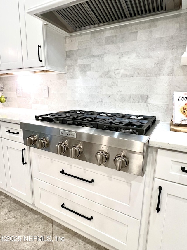2714 Las Calinas Blvd, Saint Augustine, FL 32095 - kitchen with decorative backsplash, white cabinets, range hood, light stone countertops, and stainless steel gas cooktop