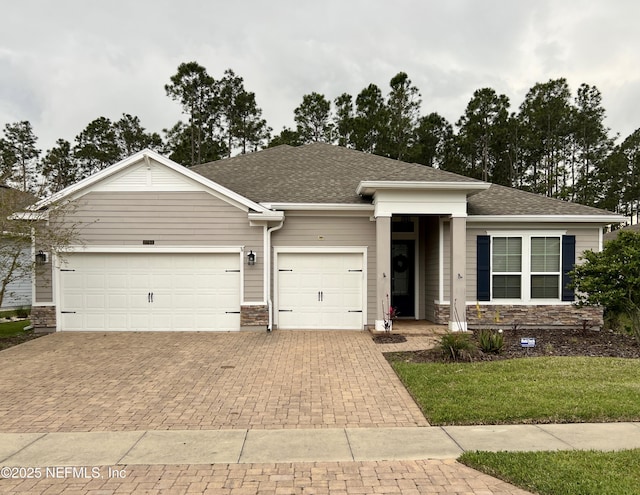 2714 Las Calinas Blvd, Saint Augustine, FL 32095 - view of front of property with stone siding, an attached garage, a shingled roof, and decorative driveway