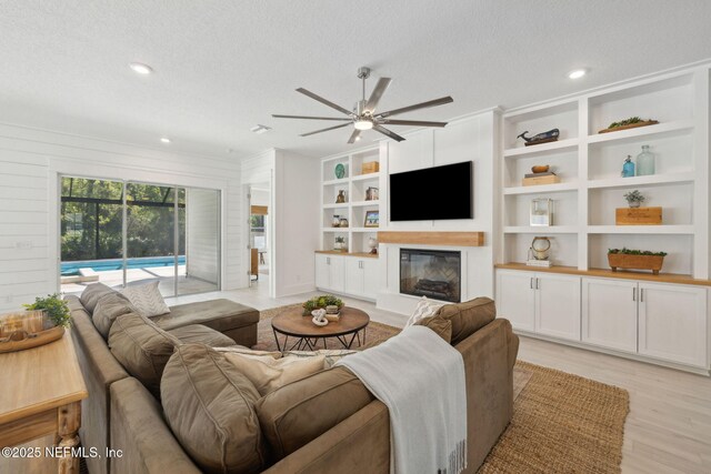280 Quail Vista Dr, Ponte Vedra, FL 32081 - living area featuring a textured ceiling, a ceiling fan, a glass covered fireplace, and light wood-type flooring