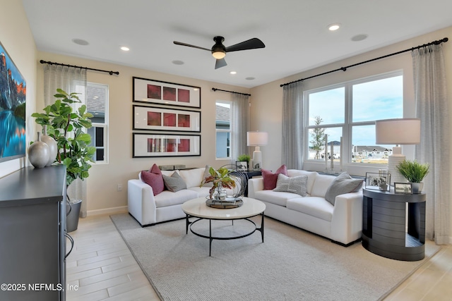 living room with light wood finished floors, baseboards, ceiling fan, and recessed lighting