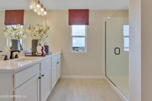 bathroom featuring baseboards, a stall shower, and vanity
