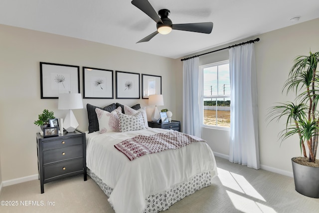 bedroom featuring light carpet, baseboards, and ceiling fan