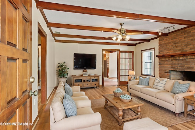 54223 Lisa Dr, Callahan, FL 32011 - living room featuring light wood-type flooring, beamed ceiling, a ceiling fan, a fireplace, and baseboards